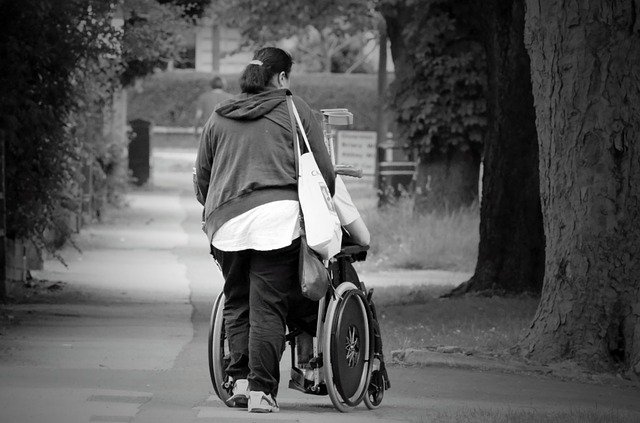 Wife is pushing her disabled husband's wheelchair