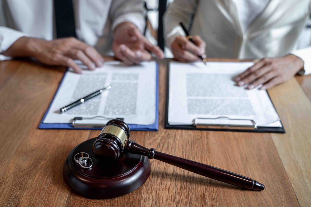 Judge gavel and two golden marriage ring, a couple is signing on a divorce agreement