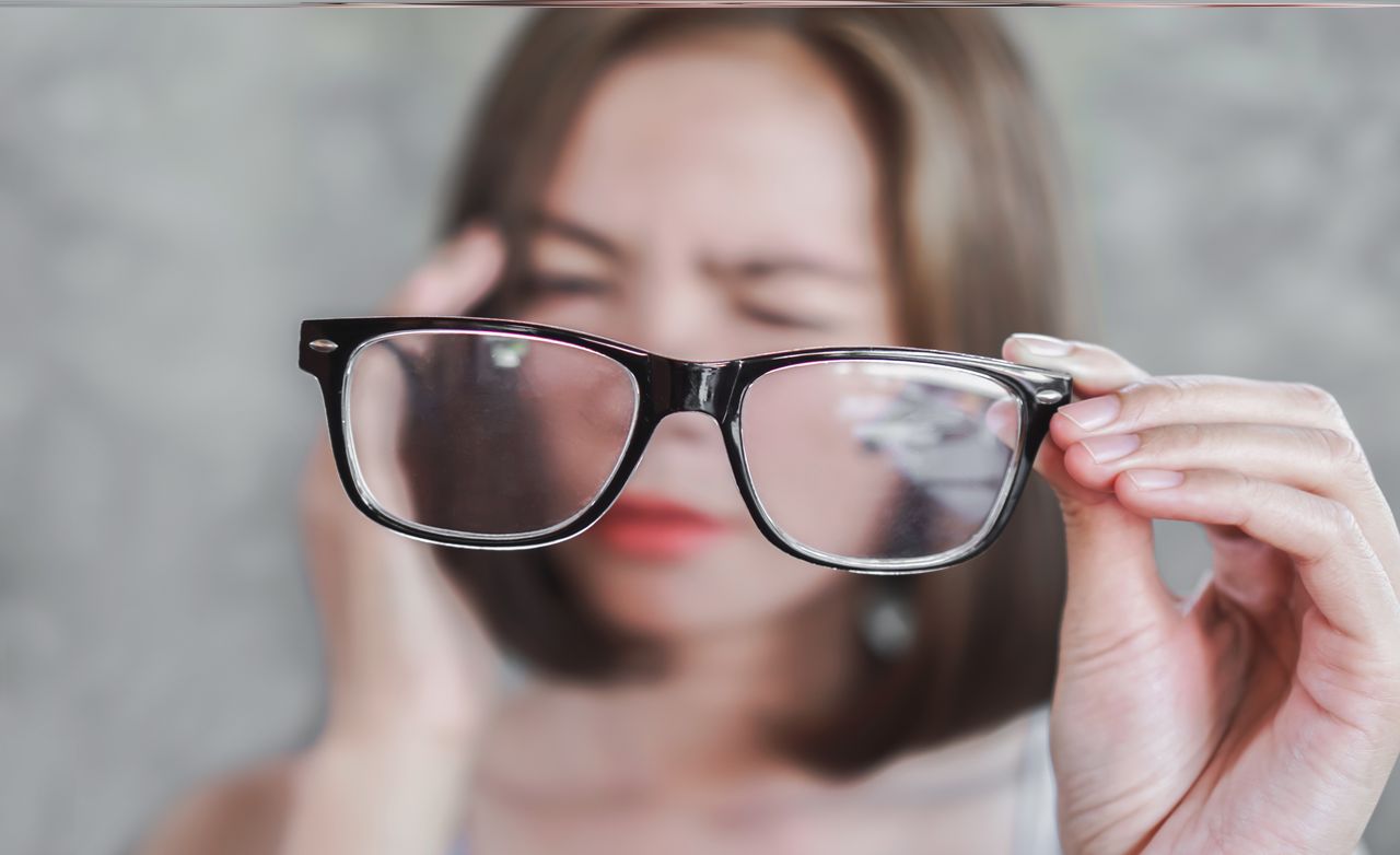 Woman has a poor vision, holding an eyeglass