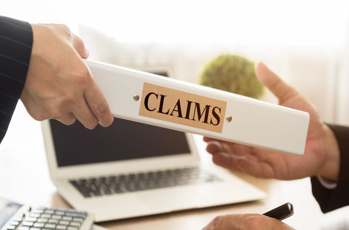 A person is delivering a claims folder to another person