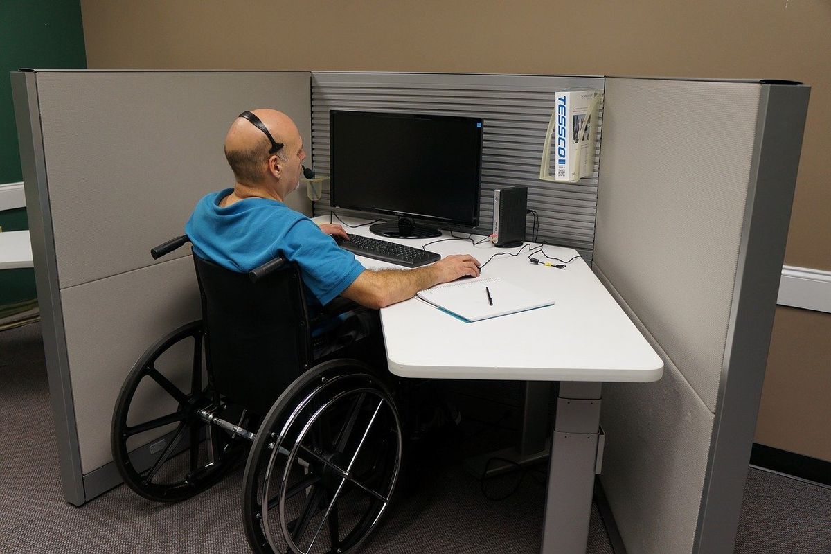 Man in wheelchair looking at computer, disabled while working